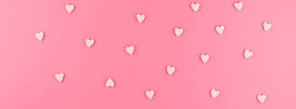 Valentines day pattern background flat lay top view of pink heart shaped candies scattered on pink background love wedding concept. Long wide banner
