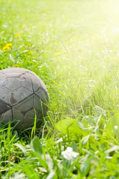 Old soccer ball forgotten in the green grass field. The football concept