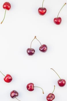 Creative top view of fresh ripe cherry pattern layout with copy space isolated on white background in minimal style. Concept of summer fun and healthy eating. Template for your text or food design