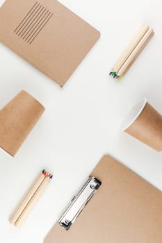 Creative top view flat lay of workspace desk styled recycled brown design office supplies and coffee cups with copy space white table background minimal eco style. Concept of environmental protection