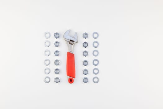 Creative knolling Flat lay of metal nuts and spanner on white background with copy space. Repair or improvement top view concept.