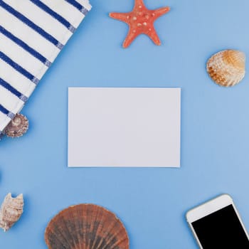 Creative square flat lay concept of summer travel vacations. Top view of beach towel, seashells, starfish and smartphone on pastel blue background with copy space in minimal style, template for text