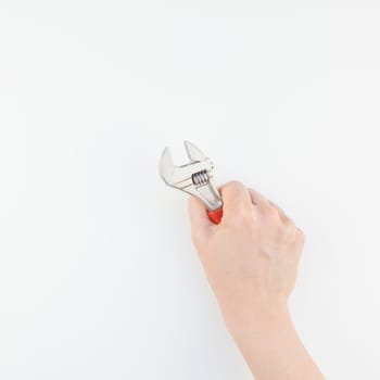 Creative square image of woman hand with pastel manicure polish holding spanner with copy space isolated on white background in minimalism style. Repair or improvement feminism concept