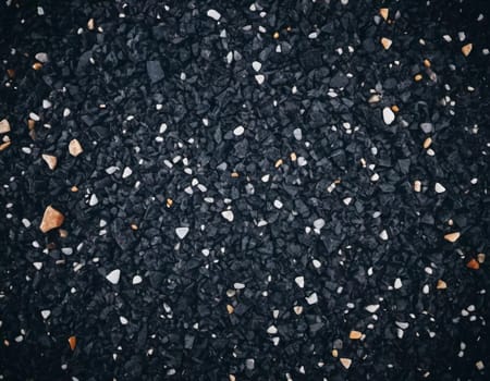 Intricate patterns of dark granite chips, illuminated by subtle lighting that creates a calm and elegant atmosphere. The black crushed mineral sparkles. Bokeh or drops. Generative AI.
