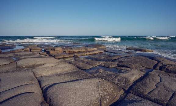 The rocky headland at Point Cartwright juts out into the sea with surf waves crashing over it. The smooth surface of the rocks make easy walking to explore it's rockpools.