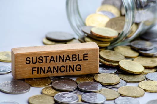Sustainable Financing text on white wooden block with coins and jar background. Sustainable Finance concept