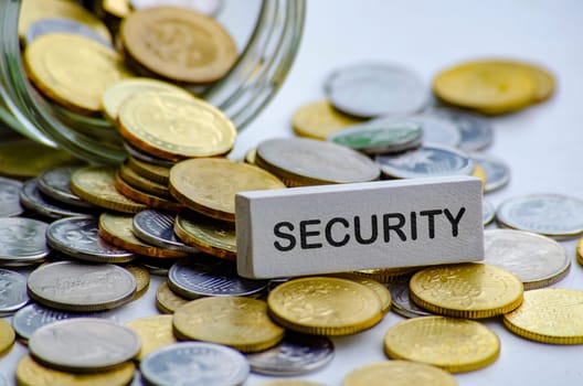 Security text on white wooden block with coins and jar background. Life security concept.