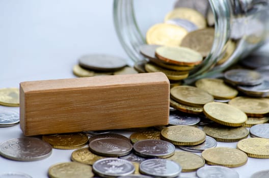 Wooden block with customizable space for text surrounded by coins with jar. Copy space concept