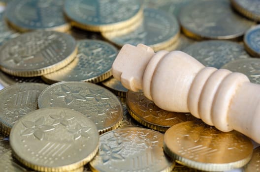 Close up of King chess on top of golden coins representing wealth and power.