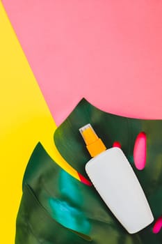 Tropical jungle palm monstera leaves and sunscreen blank bottle mockup on bright yellow and pink duotone paper background. Summer vacations creative flat lay concept template for text