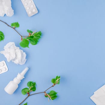 Creative flat lay concept of seasonal spring pollen allergy with napkins, pills, face mask, drops in a bottle and fresh green sprouts with buds. Square copy space background minimal style, template for text