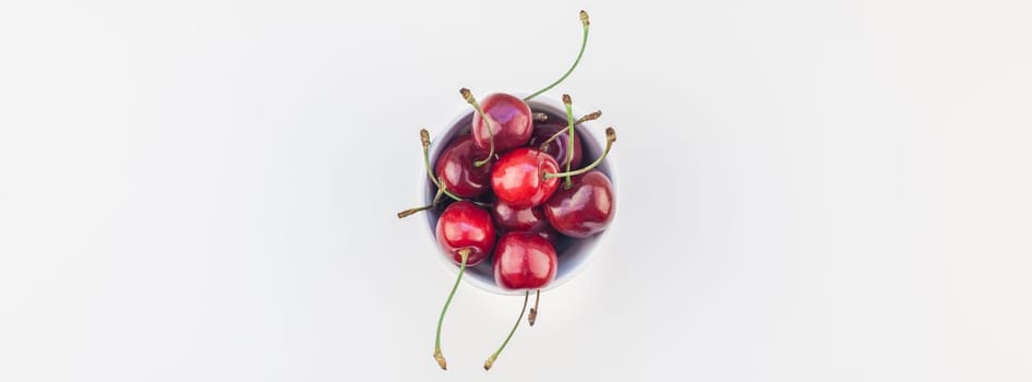Long wide banner of fresh ripe cherry in a bowl with copy space isolated on white background in minimal style. Concept of summer fun and healthy eating. Template for your text or food design