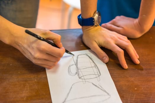 woman hands drawing a draft of a future clay cup for pottering