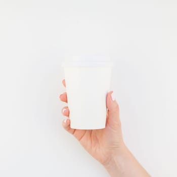 Square mock up image of woman hand holding paper coffee cup with copy space isolated on white background in minimalism style. Template for feminine blog, social media
