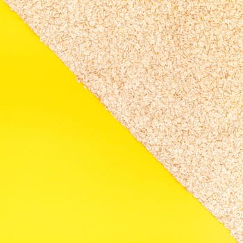 Creative flat lay concept top view of oatmeal flakes for healthy and vegetarian organic food for breakfast on a bright yellow color paper background with copy space in minimal style, square template