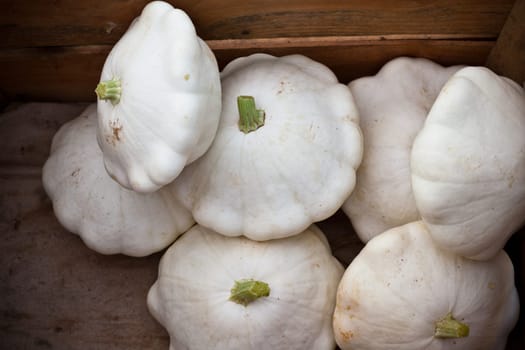 White custard marrows in a wooden box on a farm market