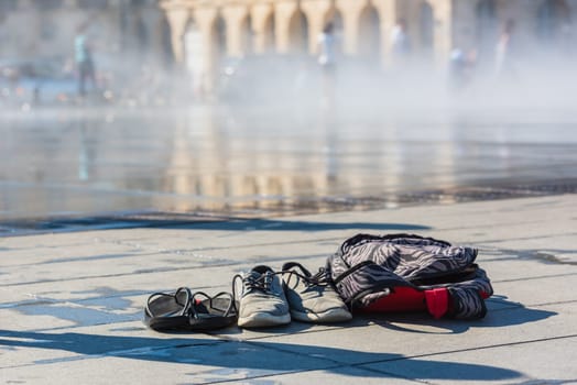 Family Shoes and a backpack left near the mirror fountain in Bordeaux, France