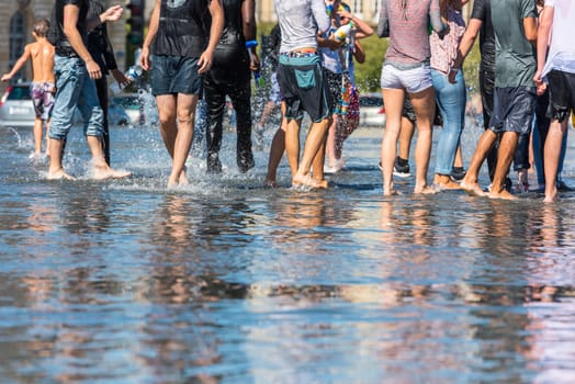 People having fun in a mirror fountain in front of Place de la Bourse in Bordeaux, France