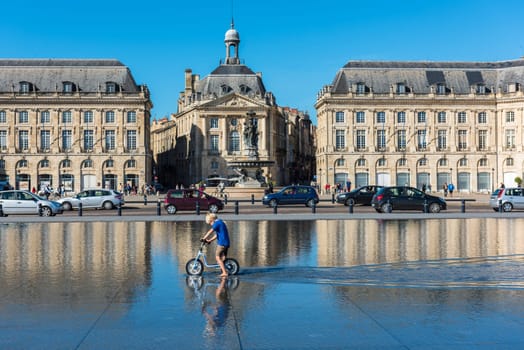 FRANCE, BORDEAUX - SEPTEMBER 20: Children having fun in a mirror fountain in front of Place de la Bourse in Bordeaux, France on September 20, 2015