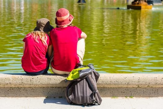 FRANCE, PARIS - JUNE 06: Best friends teenagers sitting at the fountain in summer park on June 06, 2015