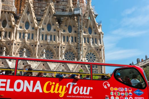SPAIN, BARCELONA - SEPTEMBER 13: People sitting on a double decker tourist coach in front of The Sagrada Familia Cathedral in Barcelona on September 13, 2015