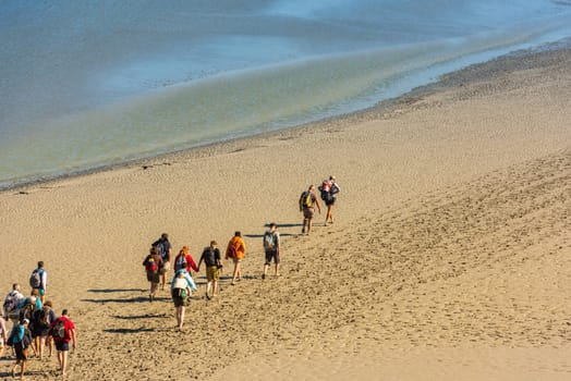 FRANCE, MONT SAINT MICHEL - SEPTEMBER 26: View from walls of Mont Saint Michel on the bay during the low tide with groups of tourists walking. France on September 26, 2015