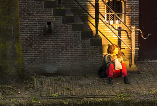 NETHERLANDS, UTRECHT - OCTOBER 01: woman sitting in light on the street of Utrecht on October 1, 2015