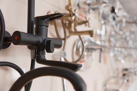 Luxury modern black chrome water tap on plumbing store display. Faucet assortment showcase in supermarket selective focus