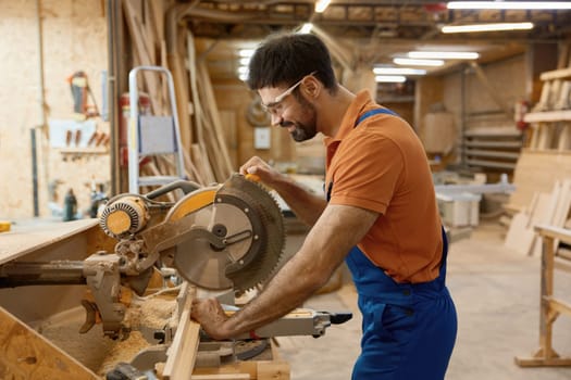 Carpenter working with circular saw enjoying craftsmanship at workshop. Professional equipment for woodwork master for wooden furniture manufacturing