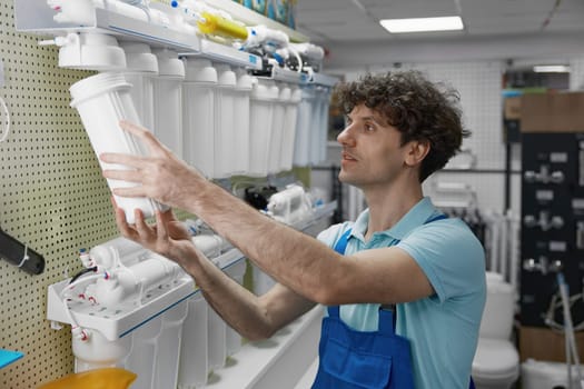 Shop assistant checking reverse osmosis filter equipment assortment at plumbing store display
