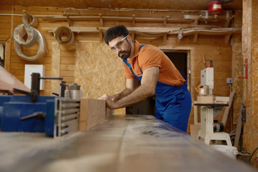 Man professional carpenter wearing workwear working with wood plank. Furniture production industry and woodworking concept