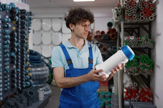 Pensive male plumber holding water pump making decision while shopping at plumbing hardware store
