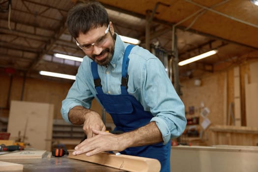 Experienced skillful woodworker using chisel manual tool at well-equipped carpentry workshop. Artistry and craftsmanship concept