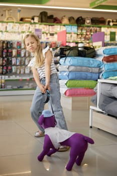 Little girl pulling nasty toy dog at pet shop. Dreams of small female kid about domestic animal friend
