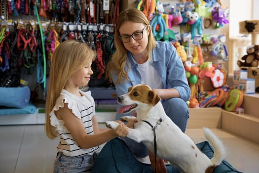 Cheerful mom and little daughter buying goods at supermarket for pets. Mother and toddler child choosing comfortable sleeping place for dog