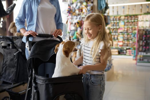Mother and daughter testing carriage for dog at pet store. Weekend family shopping together