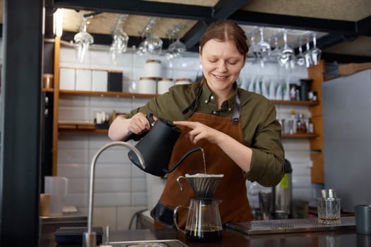 Barista hands pouring boiling water into filter coffee pot. Female cafe waiter preparing aromatic drink for client on kitchen