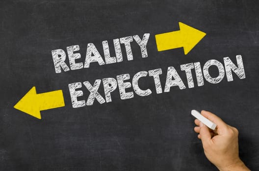 Reality or Expectation written on a blackboard