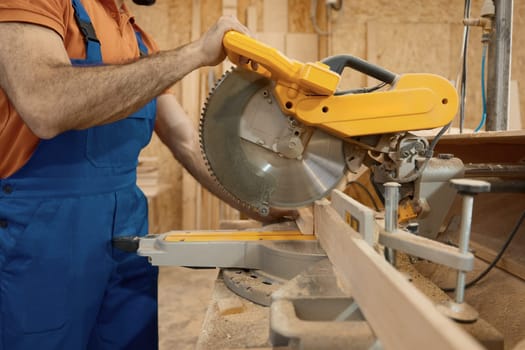 Male carpenter working with circular saw enjoying craftsmanship at workshop. Professional equipment for woodwork master for wooden furniture manufacturing