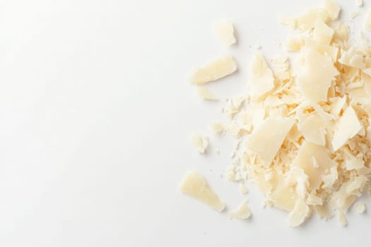 Delicate shavings of Parmesan cheese are artfully arranged on a clean white surface, perfect for enhancing various dishes. These flavorful shavings can elevate salads, pastas, and more.