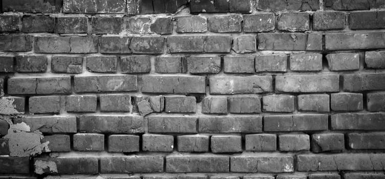 Black and white panorama of old brick wall. Texture of aged masonry with broken brick and peeling plaster. Pattern of loft interior or exterior background. Urban, grunge, industrial, abstract backdrop