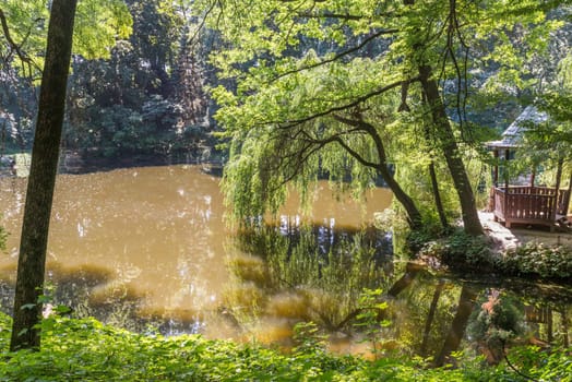 little forest lake with gazebo in a forest