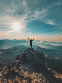 A silhouetted figure stands victoriously at the top of a dramatic mountain peak, arms outstretched against a backdrop of breathtaking alpine scenery