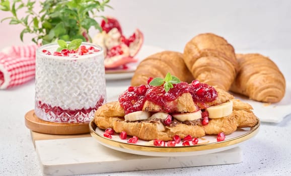 Croissant with chocolate, banana pieces and raspberry jam on a plate