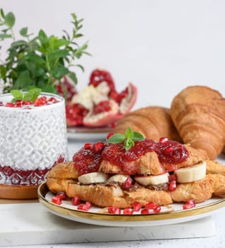 Croissant with chocolate, banana pieces and raspberry jam on a plate