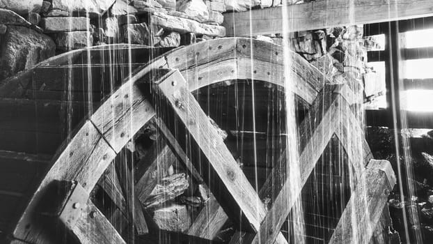 Old wooden waterwheel splashed by falling water. Picture from a watermill in Sweden by a stream.