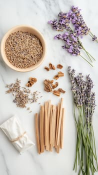 Flatlay of lavender sprigs, wooden sticks, dried herbs and natural ingredients for aromatherapy and wellness on marble background.