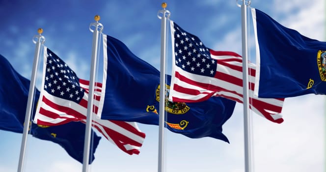 The Idaho state flags waving along with the national flags of the United States of America on a clear day. 3D illustration render. Rippled fabric. Selective focus