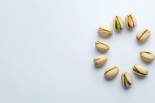 A variety of pistachios are placed in a circular formation, showcasing their unique, colorful shells. This arrangement emphasizes their vibrant green kernel and inviting snack appeal.