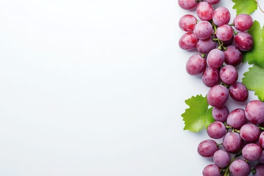 A cluster of fresh, plump grapes lies elegantly alongside vibrant green leaves on a spotless white background, highlighting their natural beauty and freshness.